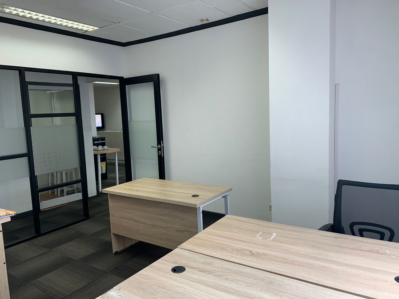 Ruang kantor dengan meja kayu dan pintu kaca berbingkai hitam